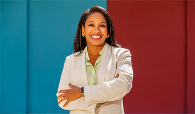 Woman in business attire smiling at camera with arms crossed
